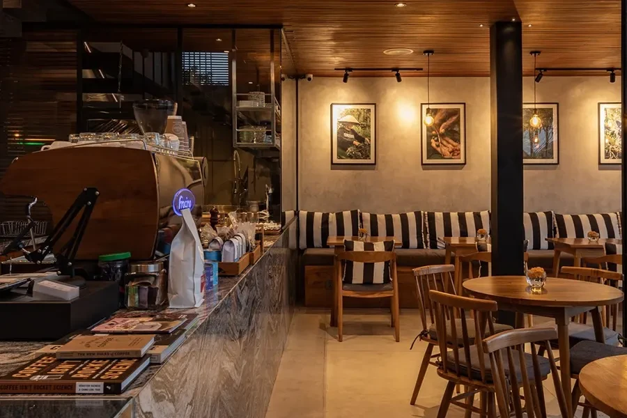 Gemini said A warm, modern cafe interior featuring wooden ceilings, industrial lighting, and a marble counter with an espresso machine.