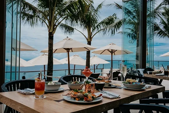 Gourmet dining table with cocktails and seafood overlooking the ocean at Oneeighty Bali.