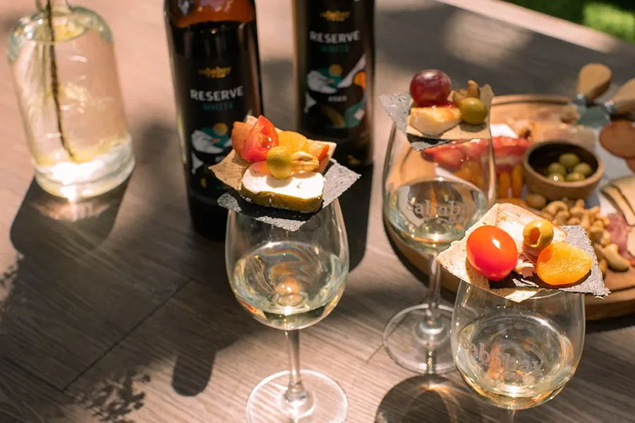 a romantic garden picnic at House of Sababay Bali, sharing gourmet appetizers at a beautifully set outdoor table with white picket fence and lush greenery.