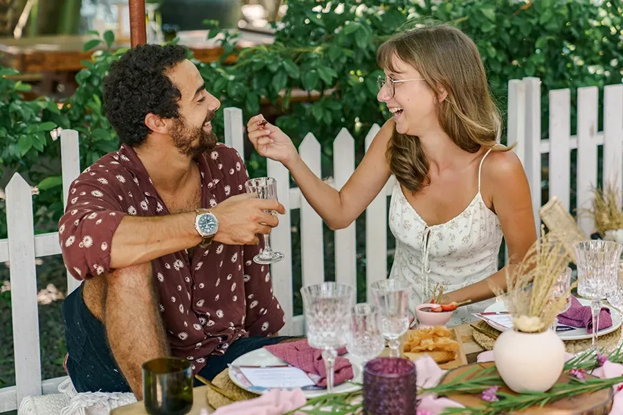 A happy couple enjoying a wine tasting and picnic lunch experience at House of Sababay, featuring an elegantly set outdoor table with crystal glasses and gourmet snacks.