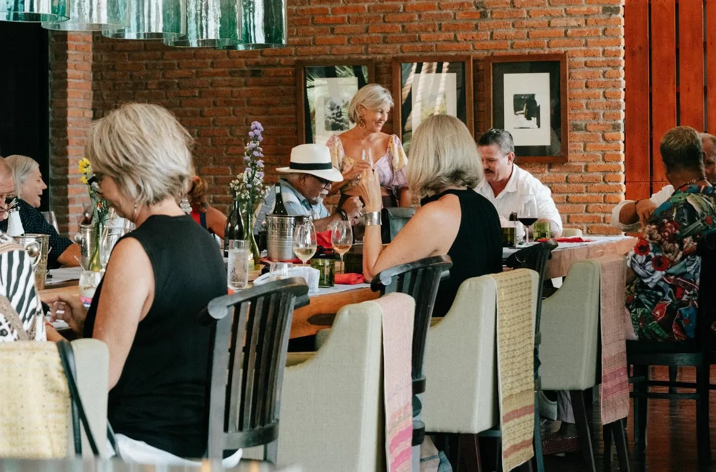 Guests enjoying a wine tasting and lunch at Hatten Wines, featuring long tables, red and white wine pairings, and a rustic brick interior in Bali.